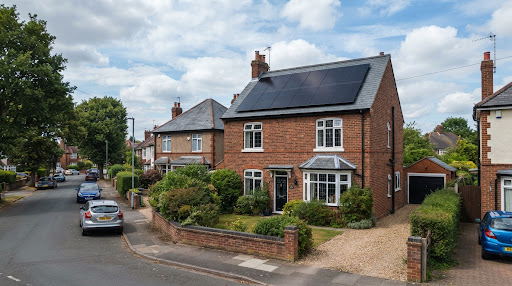 A red-brick UK semi-detached house with 10 all-black solar panels on a slate roof