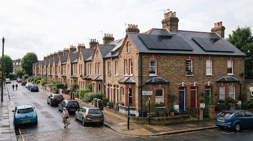 Traditional UK brick terraced houses with modern solar panels installed on pitched slate roofs